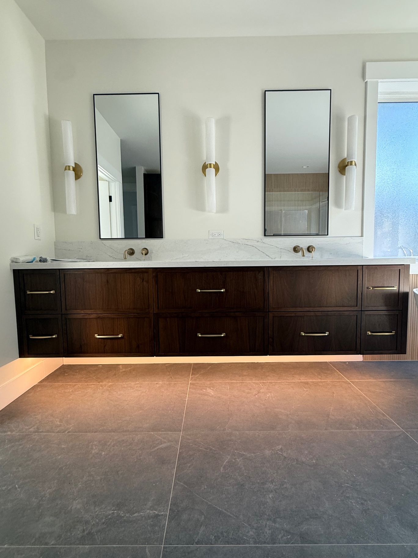 Floating walnut double vanity with brass fixtures